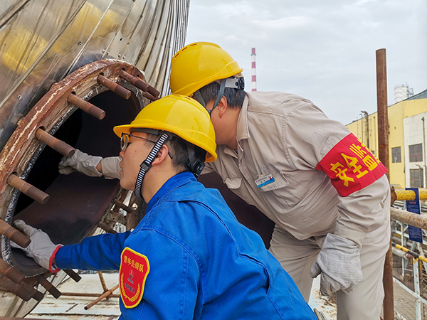 10月17日下午，在52工段除氧器人孔外，屈煒正在給董宇斌講述內部構造及工作原理。.jpg