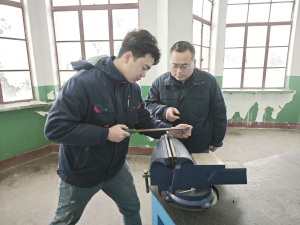 1705624316764512.jpeg 技術(shù)能手——郭峰峰正在指導青工張帆鉗工操作技能.jpg